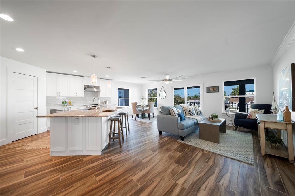 An open-concept kitchen and living area features white cabinetry, a large island, and wood-look flooring — 15564 BERTRAM DRIVE, HUDSON, FL