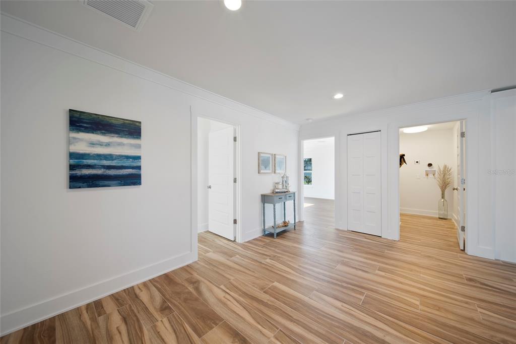 A hallway with wood-look tile flooring, white walls, and multiple doorways leading to other rooms — 15564 BERTRAM DRIVE, HUDSON, FL