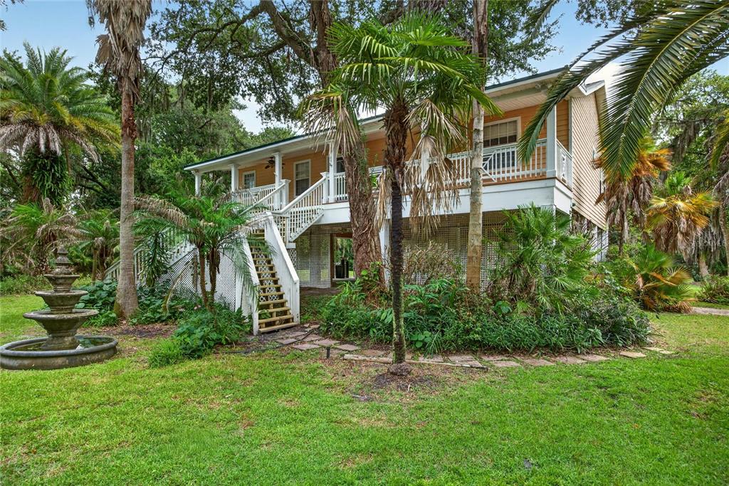 A two-story house with a raised deck, white railings, and a tiered fountain in the yard — 8435 FLORENCE COVE ROAD, ST AUGUSTINE, FL