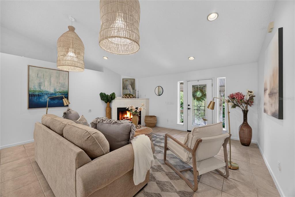 A living room features a fireplace, a beige sofa, an armchair, and two woven pendant lights — 8435 FLORENCE COVE ROAD, ST AUGUSTINE, FL