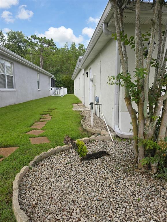 A side yard with a gravel garden bed, stepping stones, and a white fence — 20008 NOB OAK AVENUE, TAMPA, FL