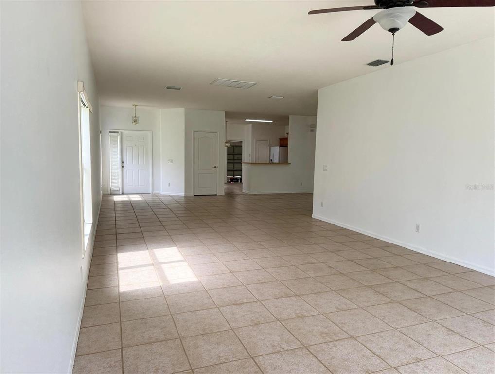 An open-concept living area features light-colored tile flooring, white walls, and a ceiling fan — 20008 NOB OAK AVENUE, TAMPA, FL