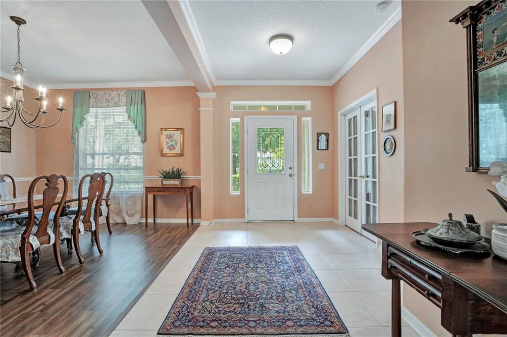A foyer with tile flooring and a rug leads to a dining room with wood floors — 8344 BOWDEN WAY, WINDERMERE, FL