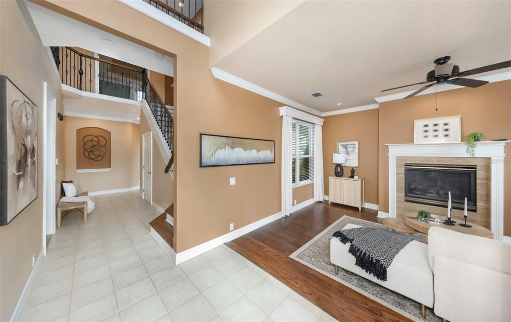 A living room with hardwood floors, a fireplace, and an adjacent tiled entryway with stairs — 313 10TH AVENUE E, PALMETTO, FL