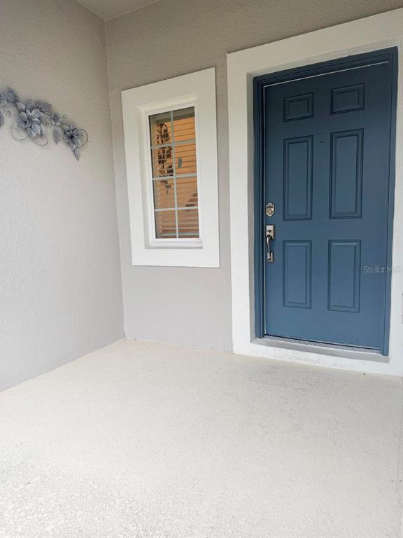A blue front door and a window are visible on a covered concrete porch — 3594 DAVENPORT CREEK COURT, KISSIMMEE, FL