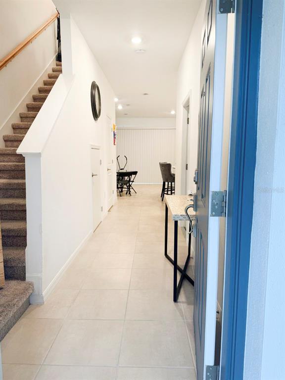A view from an entryway looking down a tiled hallway toward a dining area — 3594 DAVENPORT CREEK COURT, KISSIMMEE, FL