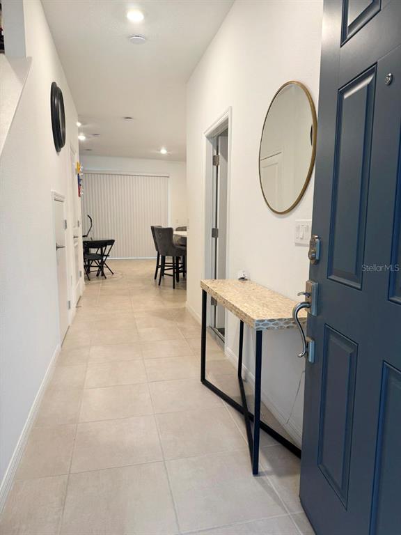 An entryway features a console table, a round mirror, and tile flooring leading to a dining area — 3594 DAVENPORT CREEK COURT, KISSIMMEE, FL