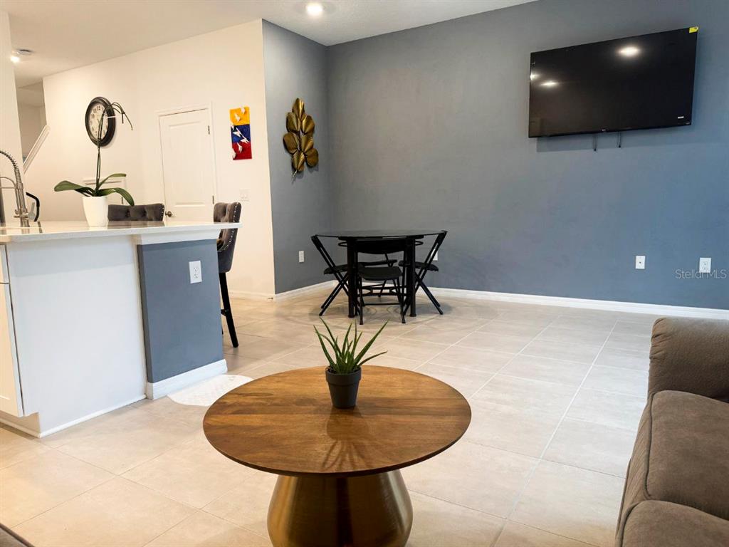 A living area features a round coffee table, a dining set, and a wall-mounted television — 3594 DAVENPORT CREEK COURT, KISSIMMEE, FL