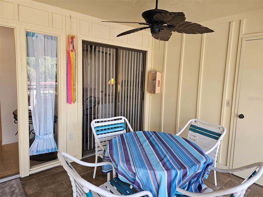 A covered patio features a round table with chairs, a ceiling fan, and sliding glass doors — 6468 SEAGULL DRIVE UNIT 316, BRADENTON, FL