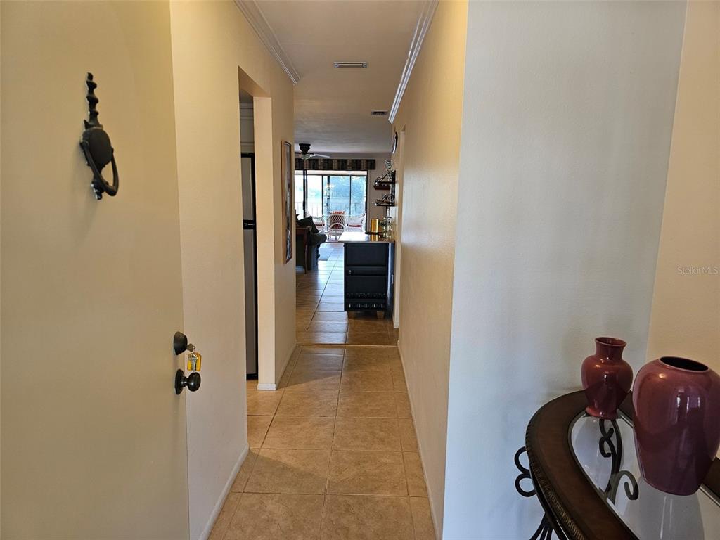 A tiled hallway leads from a foreground entryway toward a living area with patio views — 6468 SEAGULL DRIVE UNIT 316, BRADENTON, FL
