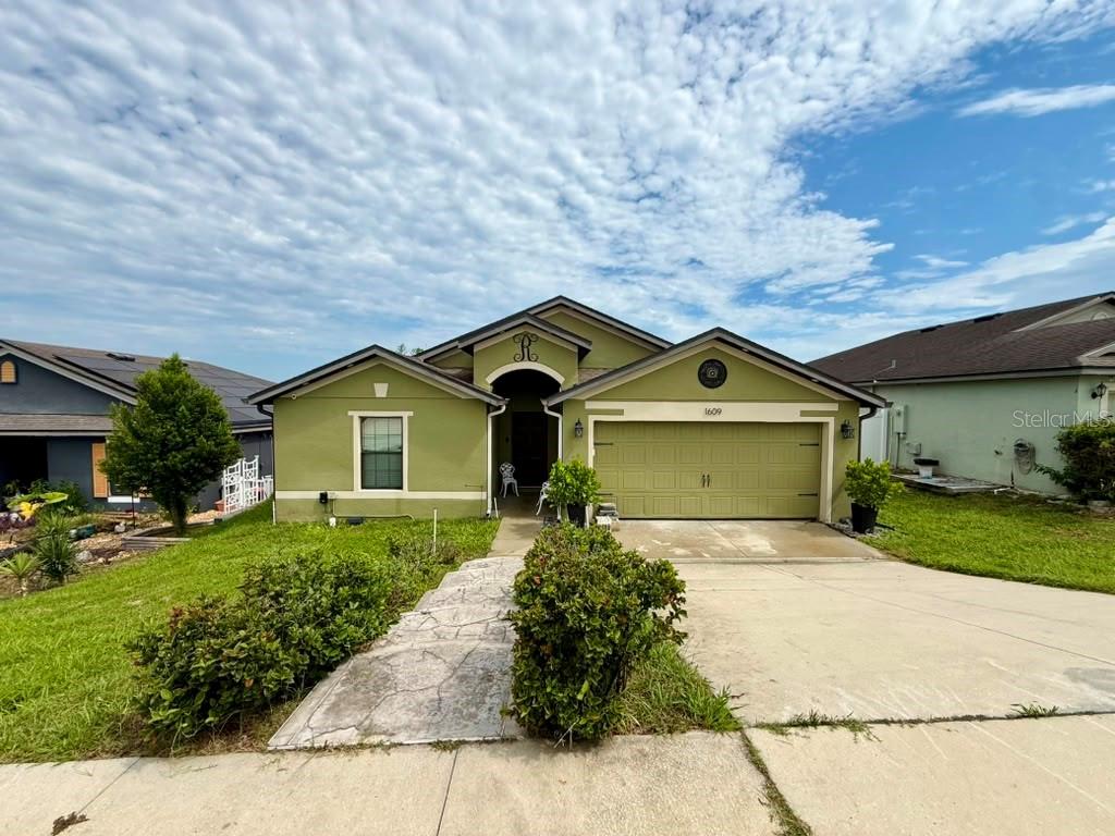 A single-story house with a green exterior, a two-car garage, and a concrete walkway — 1609 STEELY DRIVE, DUNDEE, FL