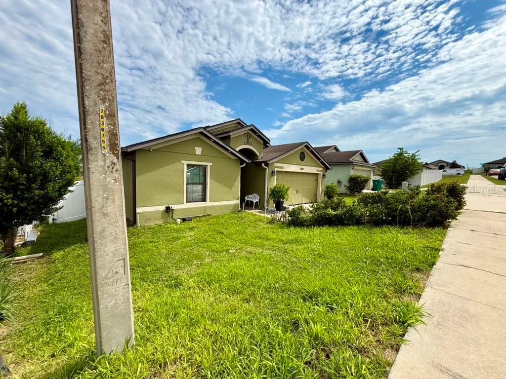A single-story house with green stucco siding, a two-car garage, and a front lawn — 1609 STEELY DRIVE, DUNDEE, FL