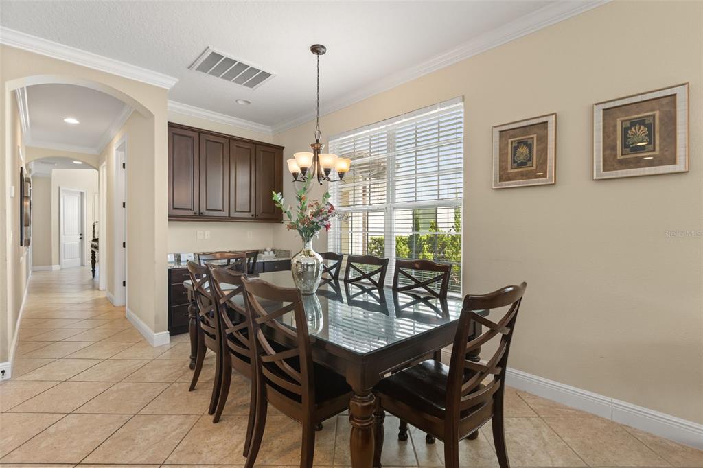 A living room with leather furniture, a large television, and sliding doors opening to a pool — 796 DESERT MOUNTAIN COURT, KISSIMMEE, FL