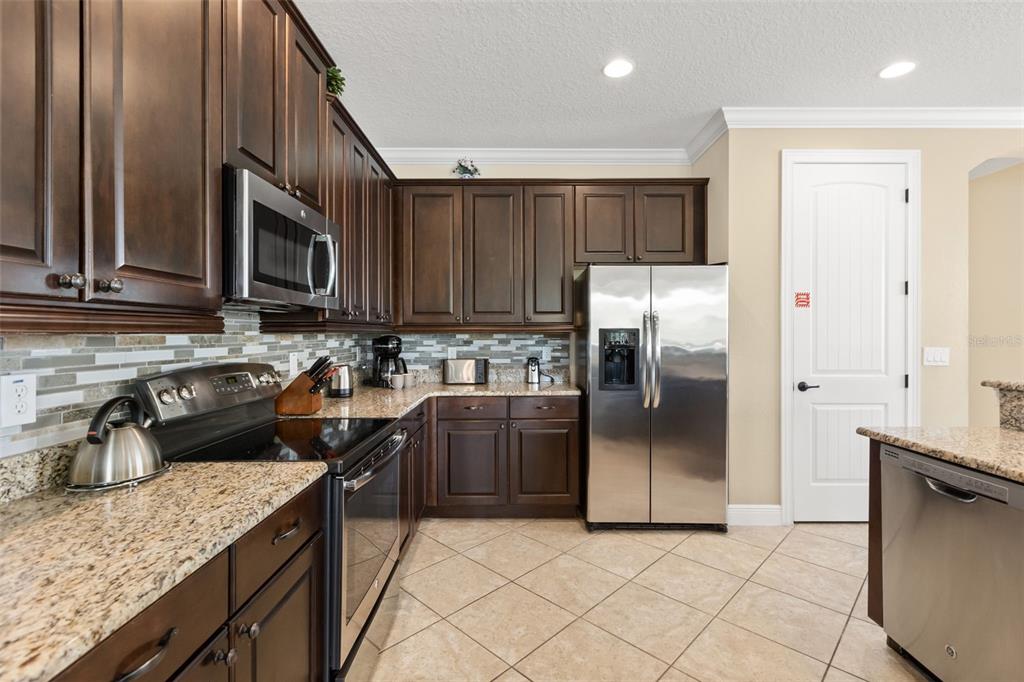 A dining room features a glass-topped table, dark wood chairs, and a built-in buffet cabinet — 796 DESERT MOUNTAIN COURT, KISSIMMEE, FL