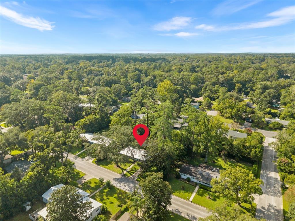 An aerial view shows a residential neighborhood with houses surrounded by many mature trees — 3525 NW 50TH AVENUE, GAINESVILLE, FL