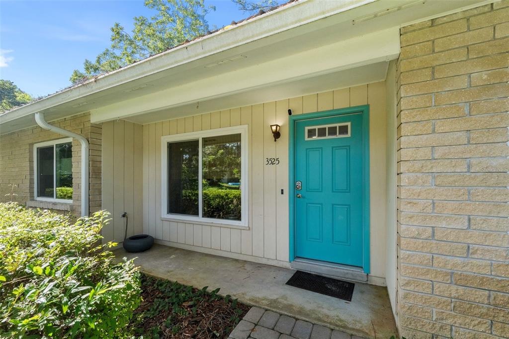 A teal front door is centered on the exterior wall of a brick and siding house — 3525 NW 50TH AVENUE, GAINESVILLE, FL