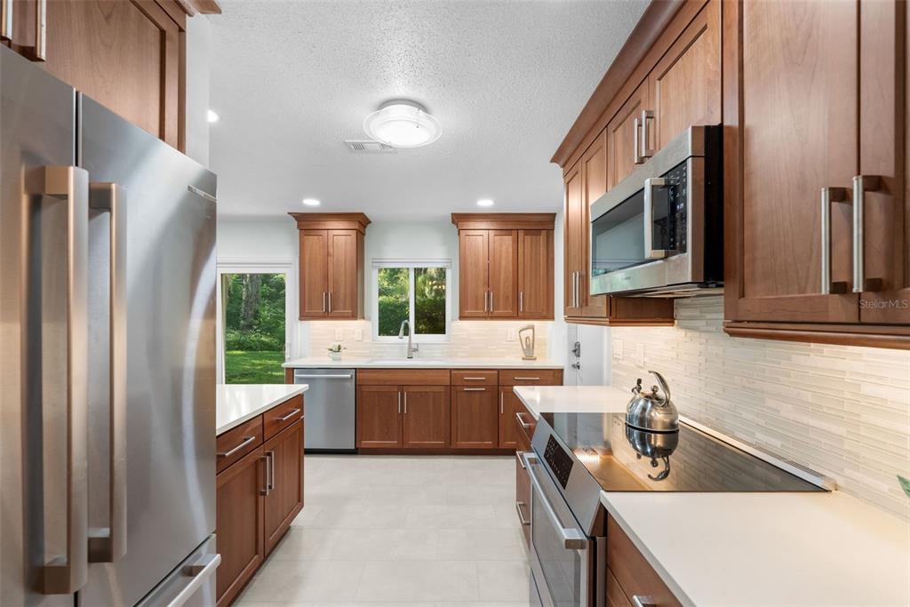 A kitchen features wood cabinets, stainless steel appliances, white countertops, and a view of greenery — 3525 NW 50TH AVENUE, GAINESVILLE, FL