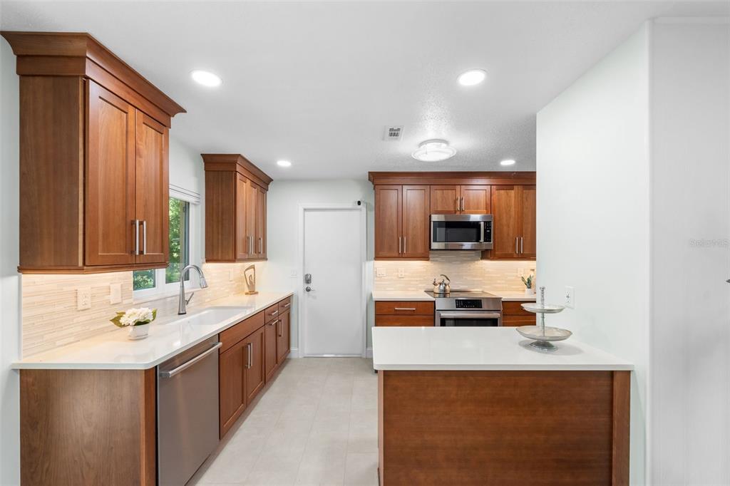 A kitchen features wood cabinets, white countertops, stainless steel appliances, and a central island — 3525 NW 50TH AVENUE, GAINESVILLE, FL