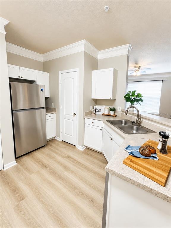 A kitchen features white cabinets, stainless steel appliances, light wood flooring, and a breakfast bar — 8813 VILLA VIEW CIRCLE UNIT 204, ORLANDO, FL