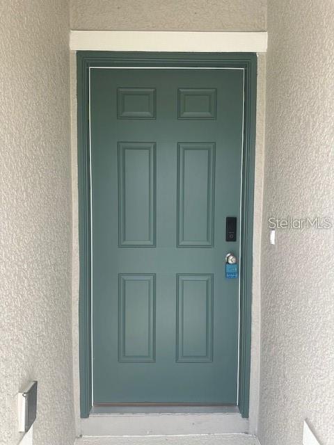 A teal six-panel front door is set within a recessed entryway with textured walls — 2432 NW 22ND COURT, OCALA, FL