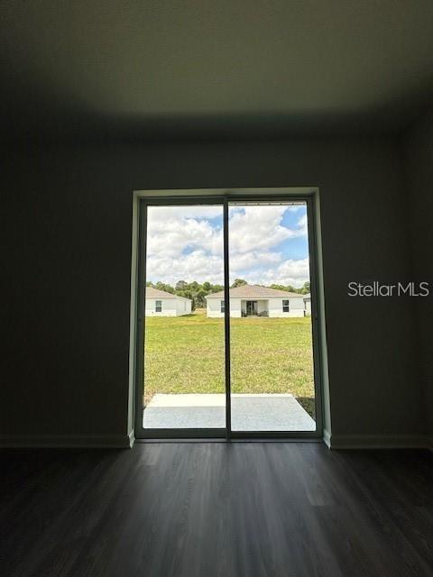 A room with dark wood-look flooring features a sliding glass door looking out onto a yard — 2432 NW 22ND COURT, OCALA, FL