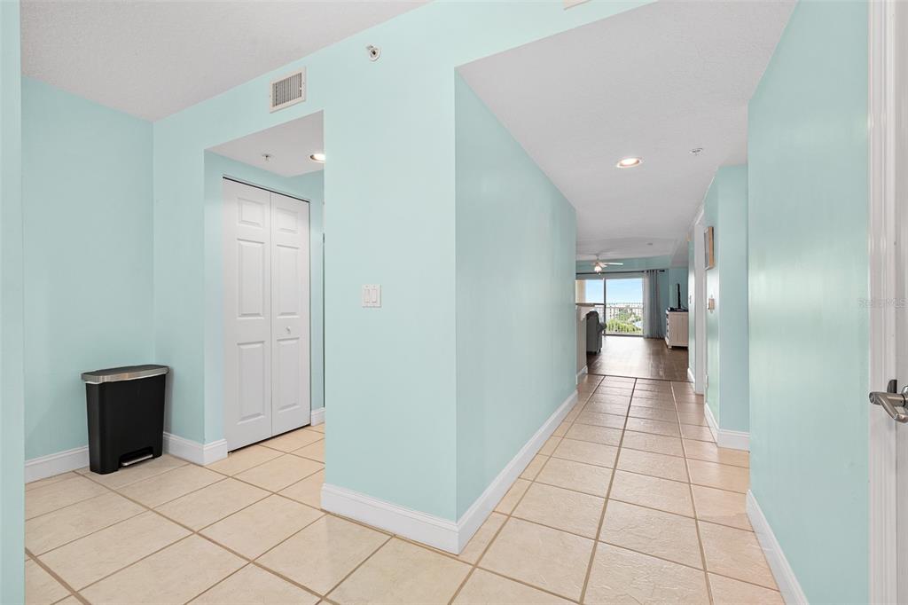 A hallway with light blue walls and beige tile flooring leads toward a living area — 4670 LINKS VILLAGE DRIVE UNIT B606, PONCE INLET, FL