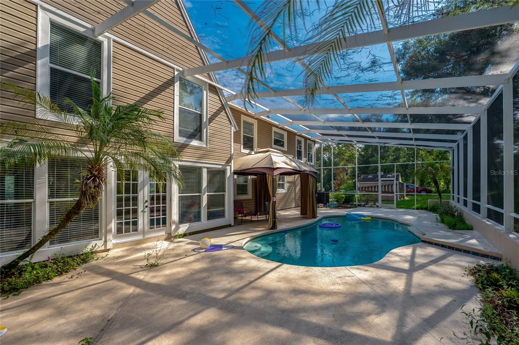 A screened-in pool area with a patio, a gazebo, and a two-story house exterior — 2081 PENNSYLVANIA DRIVE, DELAND, FL