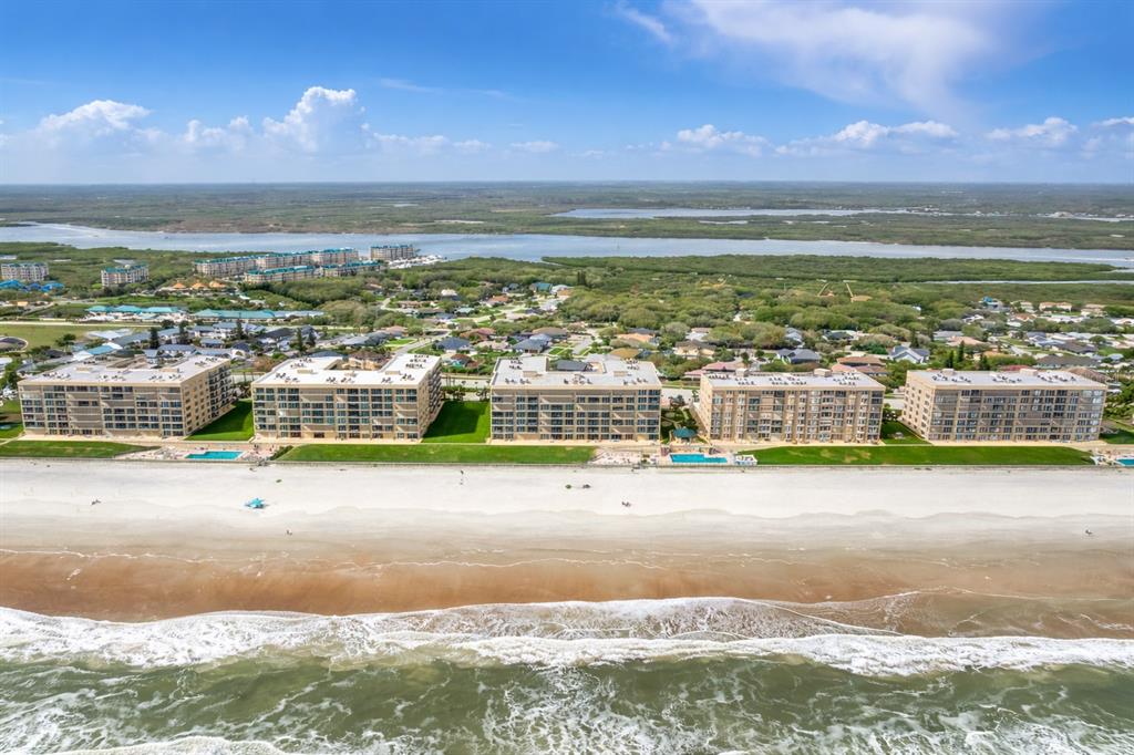 The exterior of a multi-story apartment building features balconies and a gated entrance kiosk — 4555 S ATLANTIC AVENUE UNIT 4506, PONCE INLET, FL