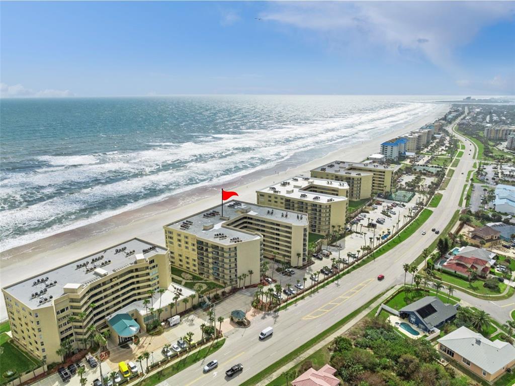 An aerial view shows three U-shaped beachfront apartment buildings with parking lots along a road — 4555 S ATLANTIC AVENUE UNIT 4506, PONCE INLET, FL