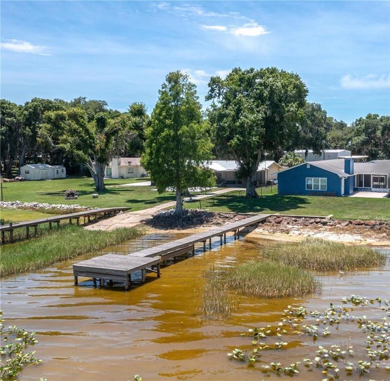 A wooden dock extends into a lake in front of a grassy yard and houses — 10742 W BEACH PARKWAY, LAKE WALES, FL