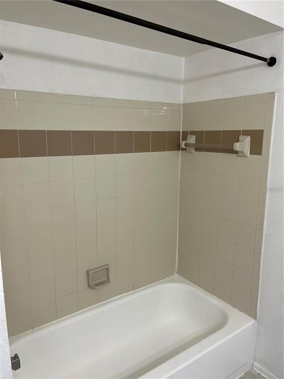 A bathtub with beige and brown tiled walls and a shower curtain rod — 1924 LAKE ATRIUMS CIRCLE UNIT 55, ORLANDO, FL