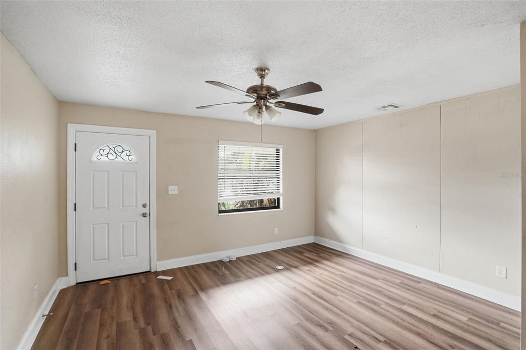 An empty room features wood-look flooring, a ceiling fan, a white door, and a window — 2131 MESSINA AVENUE, ORLANDO, FL