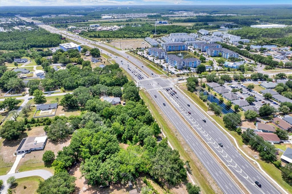An aerial view shows a multi-lane highway intersecting a road near residential and commercial buildings — STATE ROAD 54, LUTZ, FL