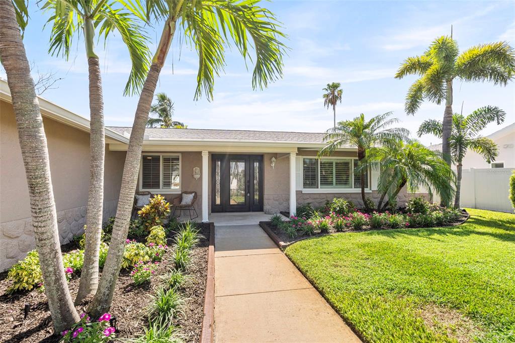 A concrete walkway leads to the front entrance of a single-story house with palm trees — 251 N JULIA CIRCLE, ST PETE BEACH, FL