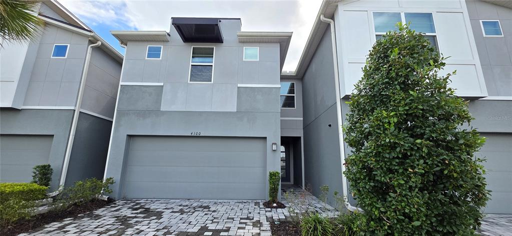 The exterior of a two-story gray townhouse features a garage and a paved driveway — 4100 CLOUD HOPPER WAY, LUTZ, FL