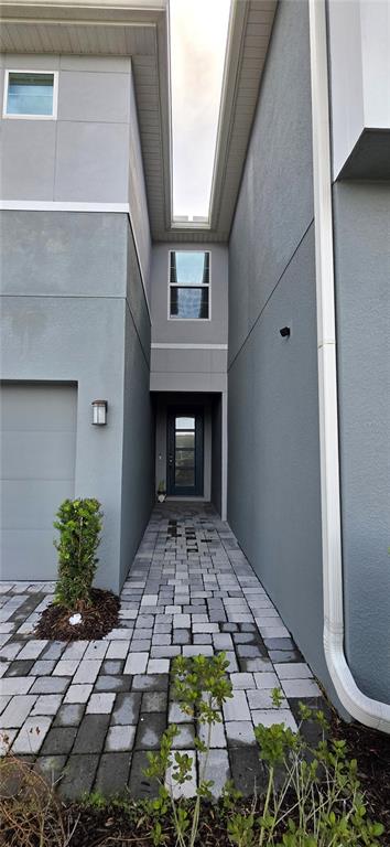 A paved walkway leads to the recessed front entrance of a modern gray two-story home — 4100 CLOUD HOPPER WAY, LUTZ, FL