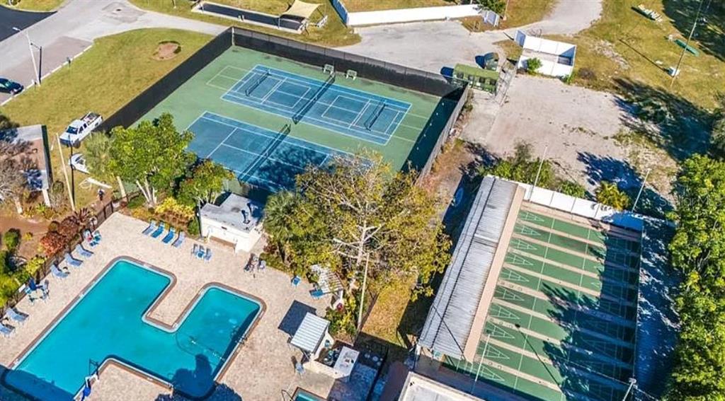 An aerial view shows a swimming pool, two tennis courts, and several shuffleboard courts — 5925 TERRACE PARK DRIVE N UNIT 111, ST PETERSBURG, FL