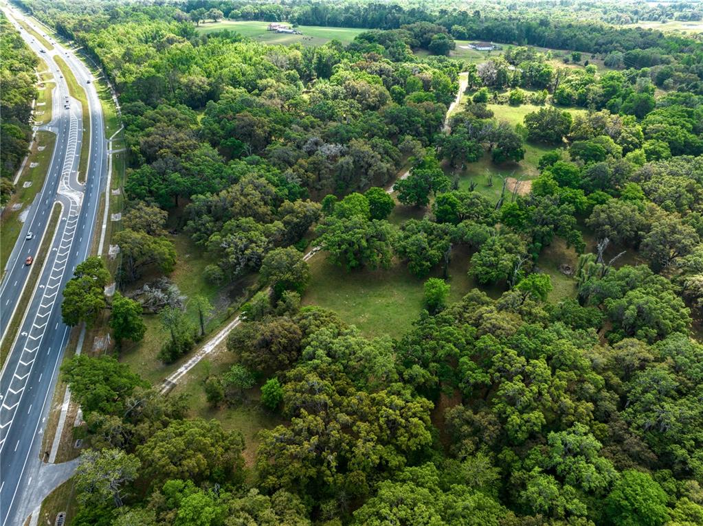An aerial view shows a wooded lot adjacent to a multi-lane highway — 22374 CORTEZ BOULEVARD, BROOKSVILLE, FL