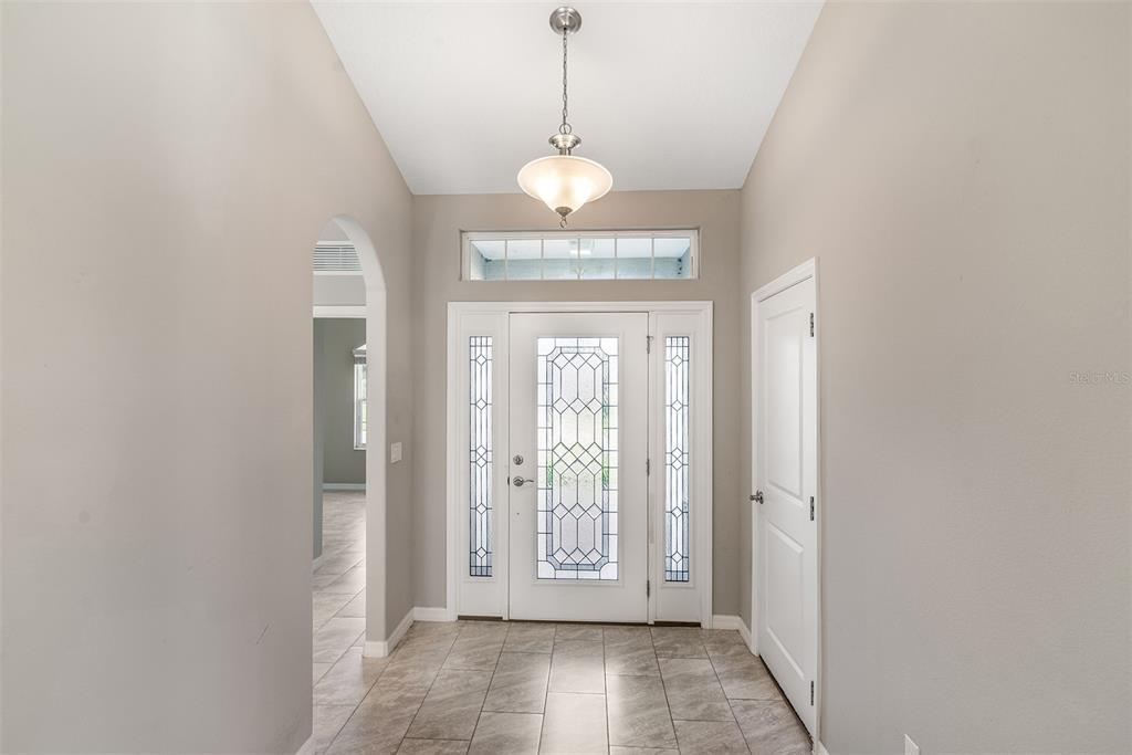 A bright entryway features tile flooring, a decorative glass front door, and a pendant light — 4 TIDEWAY TRAIL, PALM COAST, FL