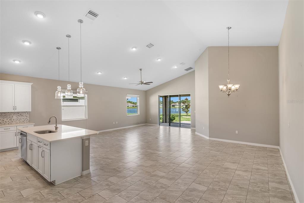 An open-concept kitchen and living area with tile flooring, white cabinets, and a sliding glass door — 4 TIDEWAY TRAIL, PALM COAST, FL