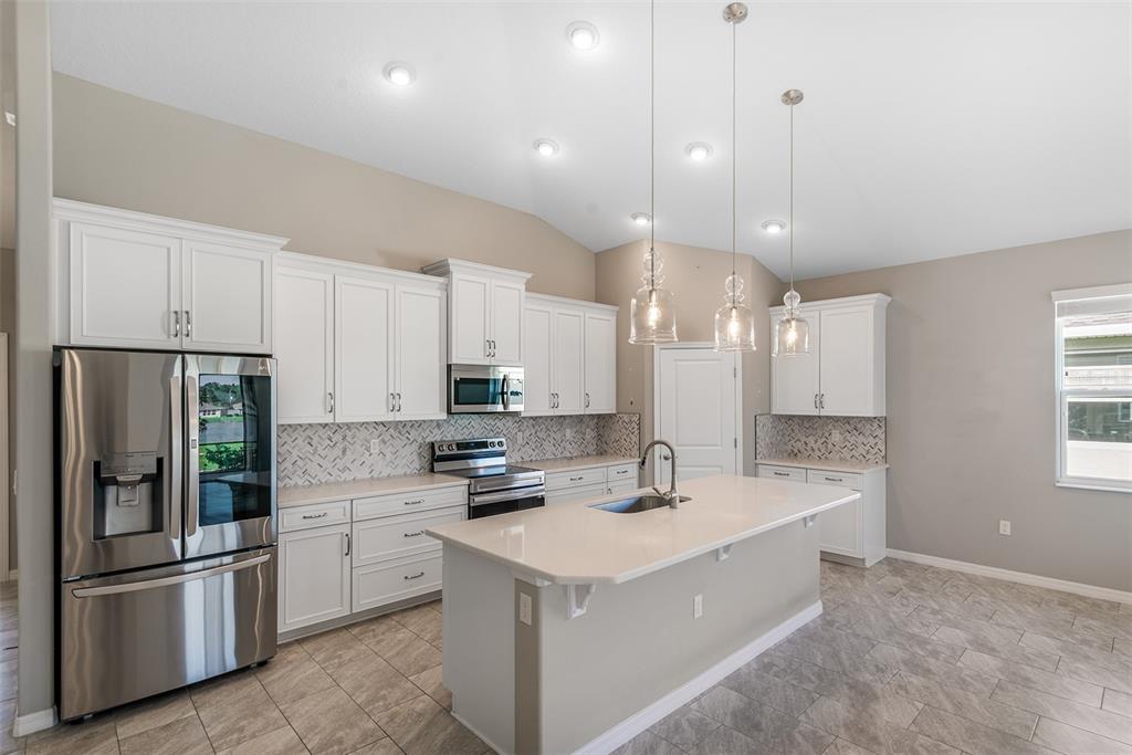 An open-concept living area features a kitchen island, dining space, and views of a lake — 4 TIDEWAY TRAIL, PALM COAST, FL