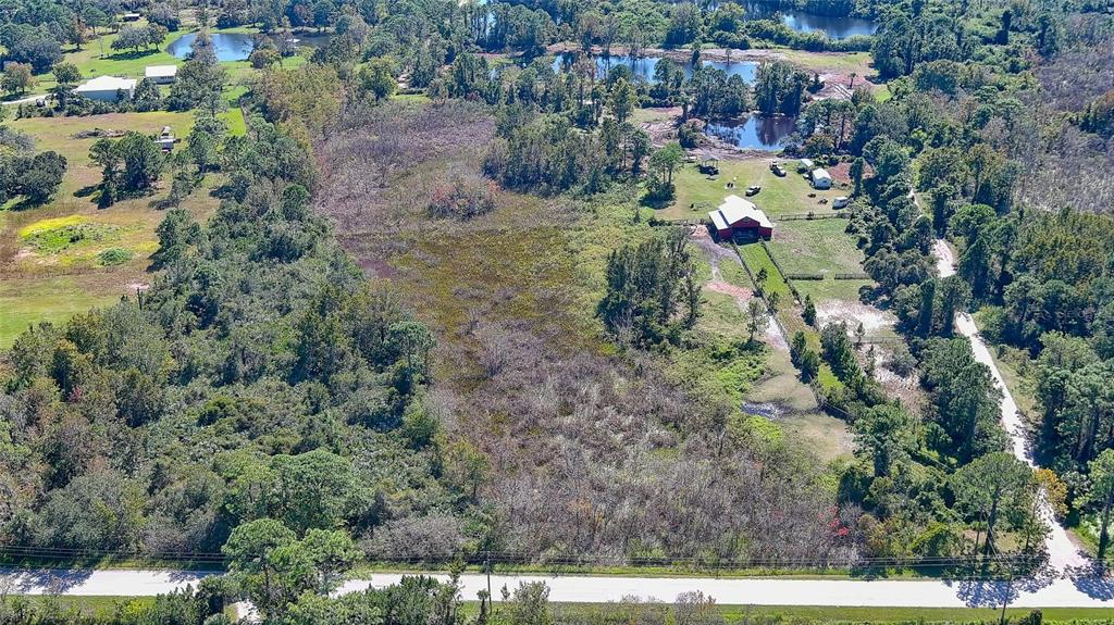 An aerial view shows a rural property with a red barn, ponds, and wooded areas — 806 W ARIEL ROAD, EDGEWATER, FL