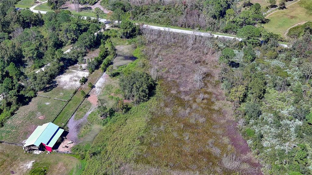An aerial view shows a rural property with a barn, pasture, and surrounding wooded areas — 806 W ARIEL ROAD, EDGEWATER, FL