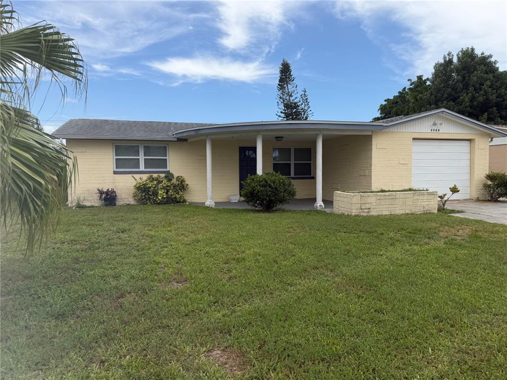 A single-story yellow brick house with a curved front porch and an attached garage — 3908 BADEN DRIVE, HOLIDAY, FL