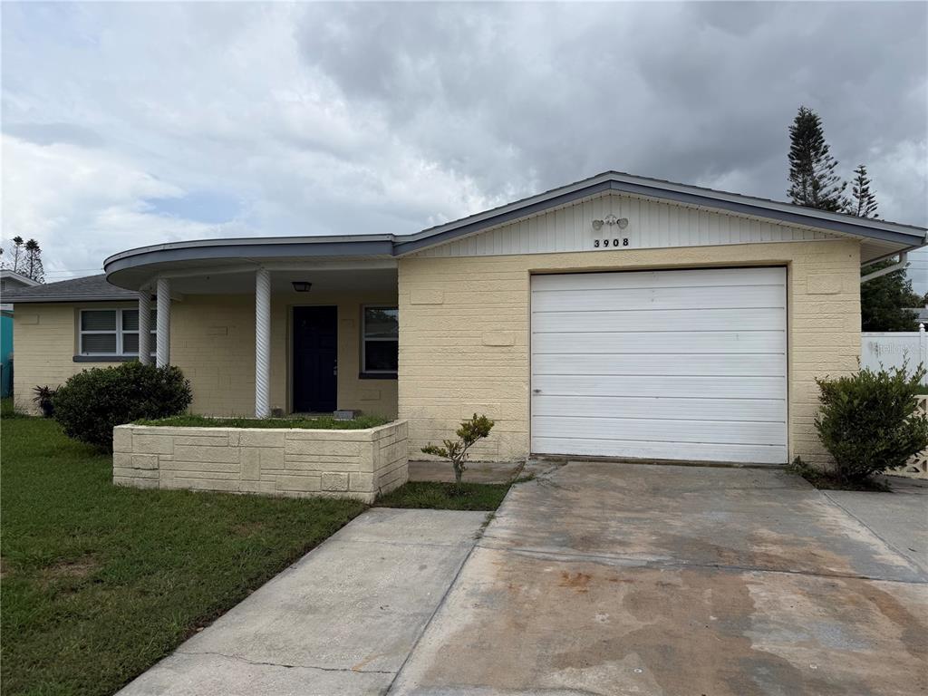 A single-story house with a yellow brick exterior, a garage, and a curved front porch — 3908 BADEN DRIVE, HOLIDAY, FL