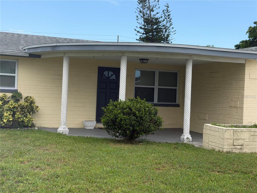 A yellow brick house features a curved front porch with two white spiral columns — 3908 BADEN DRIVE, HOLIDAY, FL