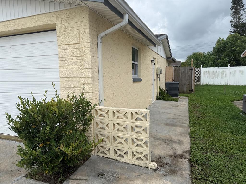 A side view of a house exterior featuring a concrete patio and decorative block wall — 3908 BADEN DRIVE, HOLIDAY, FL