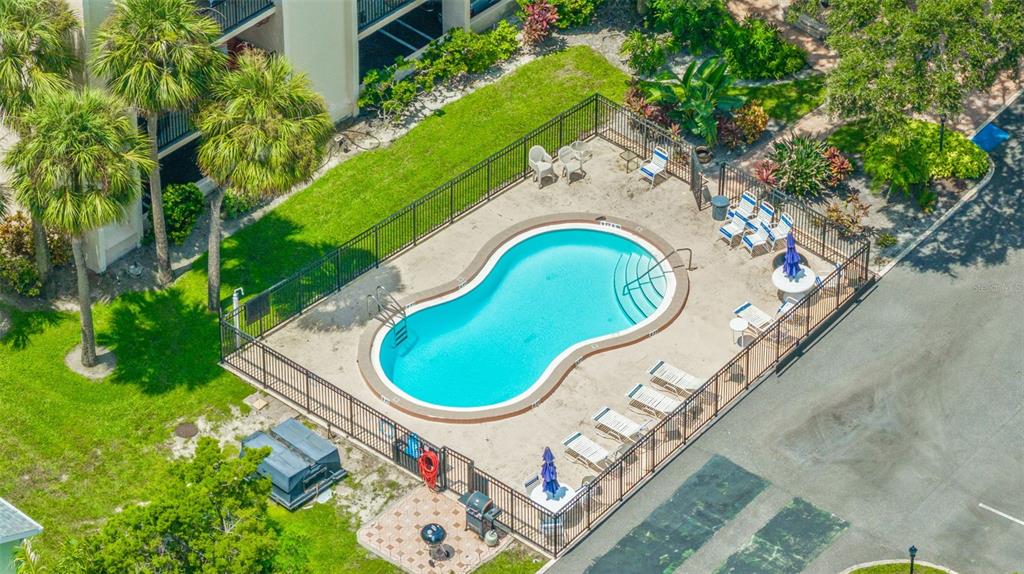 A swimming pool sits in front of a multi-story apartment building with private balconies — 402 TARPON POINT, TARPON SPRINGS, FL