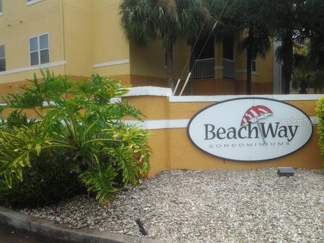 A sign for BeachWay Condominiums stands in front of a yellow building with palm trees — 10764 70TH AVENUE UNIT 1102, SEMINOLE, FL