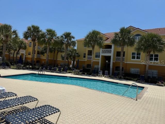 A swimming pool sits on a paved deck surrounded by palm trees and apartment buildings — 10764 70TH AVENUE UNIT 1102, SEMINOLE, FL
